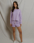 model wearing a purple lounge set on a white background