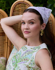 Woman sitting on a wicker chair wearing a decorative headscarf and dress