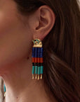 model wearing colorful earrings on a beige background