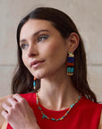 model wearing colorful earrings and necklace on a beige background