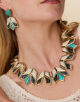 model wearing onyx and turquoise necklace and earrings on a cream background