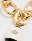Gold chain with a white and black pendant on a light gray background