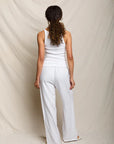 Person wearing a white sleeveless top and pants against a plain background