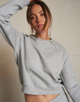 Woman wearing a gray sweatshirt and pants against a plain background