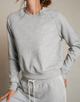 Person wearing a gray sweatshirt and pants set against a neutral background