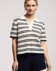 Model wearing the lumae milk and navy stripe short sleeve polo top with shorts on a white background, front