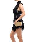 Woman holding a gold clutch purse against a white background
