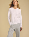 model wearing a white long sleeve tee and gray sweatpants on a beige background