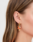 Close-up of an ear wearing a colorful earring with a plain background