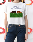 Person wearing a white t-shirt with horse graphic and 'Stable Relationship' text, standing against a colorful abstract background.