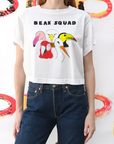Person wearing a white t-shirt with 'BEAK SQUAD' and toucan graphics against a colorful abstract background.