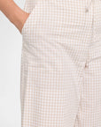 Close-up of a person wearing light beige and white gingham checkered pants, showing the side pocket and drawstring waistband.