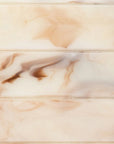 A close-up of a glossy marble-look surface with soft cream, beige, and warm brown veining and horizontal seam lines.