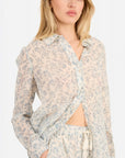 Woman wearing a floral long-sleeve top with a white background