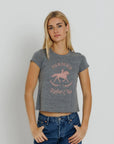 model wearing a grey tee with a pink graphic with jeans on a cream background