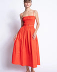 Woman wearing a bright orange dress against a white background