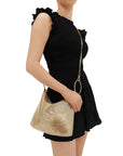 Woman holding a gold handbag wearing a black dress on a white background
