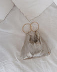 Metallic mesh bag with gold rings on a white fabric background