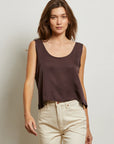 Woman wearing a brown sleeveless top and beige pants against a plain background front view