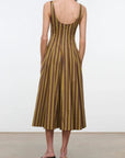 A woman shown from the back wearing a sleeveless midi dress with vertical brown and olive-gold stripes and a deep open back, paired with black heeled sandals against a plain studio background.