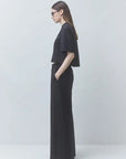 model wearing a black tshirt with black pants on a black background, side