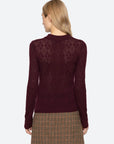 Woman wearing a burgundy sweater with a patterned design on a white background