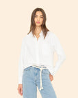 Woman wearing White Monroe Shirt and light blue jeans against a beige background
