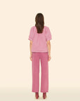 Woman wearing a pink outfit on a beige background, back