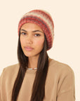 Woman wearing a striped beanie on a beige background