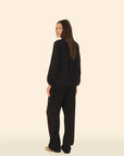 Person wearing a black outfit on a beige background