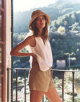 Woman standing on a balcony with a scenic view of mountains and trees.