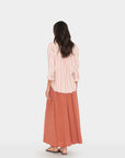 Woman wearing a striped shirt and long skirt on a white background