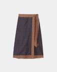 A wrap-style skirt with a dark navy base and a dense small-scale geometric pattern in brown and white, featuring a matching brown patterned waistband and tie belt.
