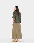 Woman wearing a green camouflage top and beige skirt on a white background