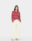 model wearing a pink and brown stripe sweater with wide leg cream sweatpants on a white background