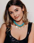 Woman wearing a black dress and turquoise necklace and pendant neckalce.