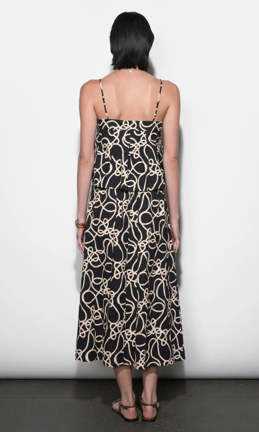Woman wearing a black dress with beige pattern against a white background