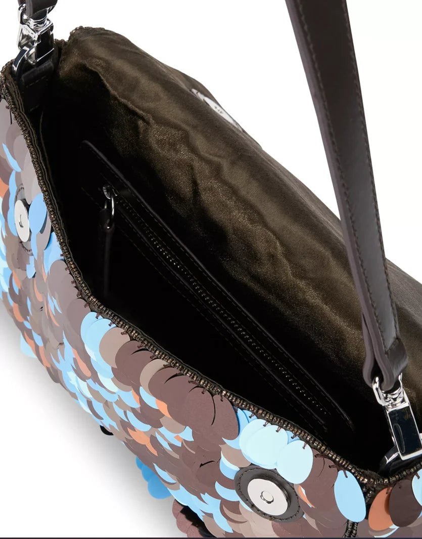 Close-up of an open handbag showing a dark brown satin interior, black zipper, and a patterned exterior with blue, brown, and orange abstract shapes on a white background.