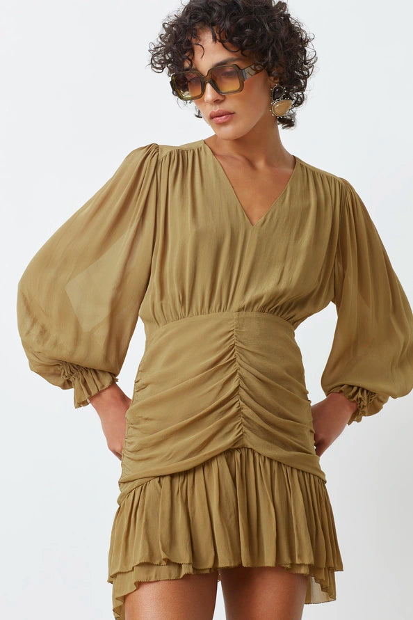 Woman wearing a beige dress with puffed sleeves on a white background