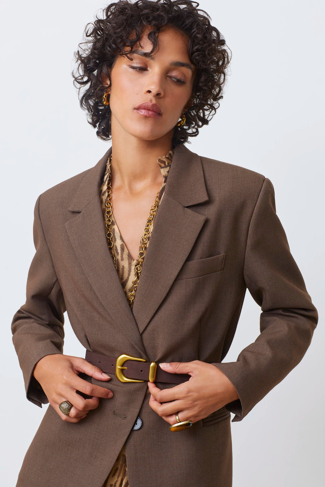 Aila choco leather belt on a model with a brown blazer with a white background