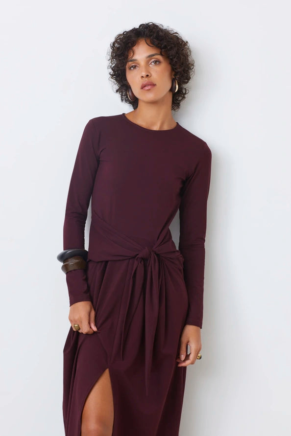 Woman wearing a burgundy dress with long sleeves against a white background front