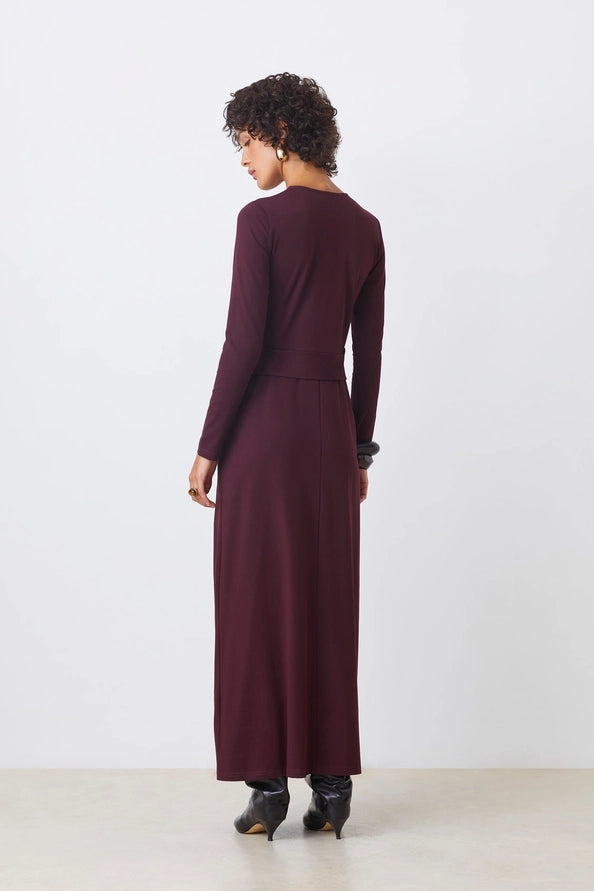 Woman wearing a long burgundy dress against a white background
