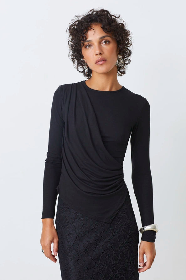 Woman wearing a black long-sleeve top with a draped design on a white background