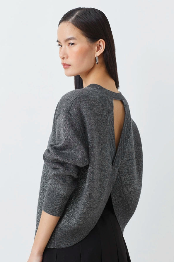 Woman wearing a gray open-back sweater against a white background