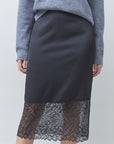 A model wearing a dark charcoal gray midi skirt with a sheer black floral lace hem, paired with a heather gray knit sweater.