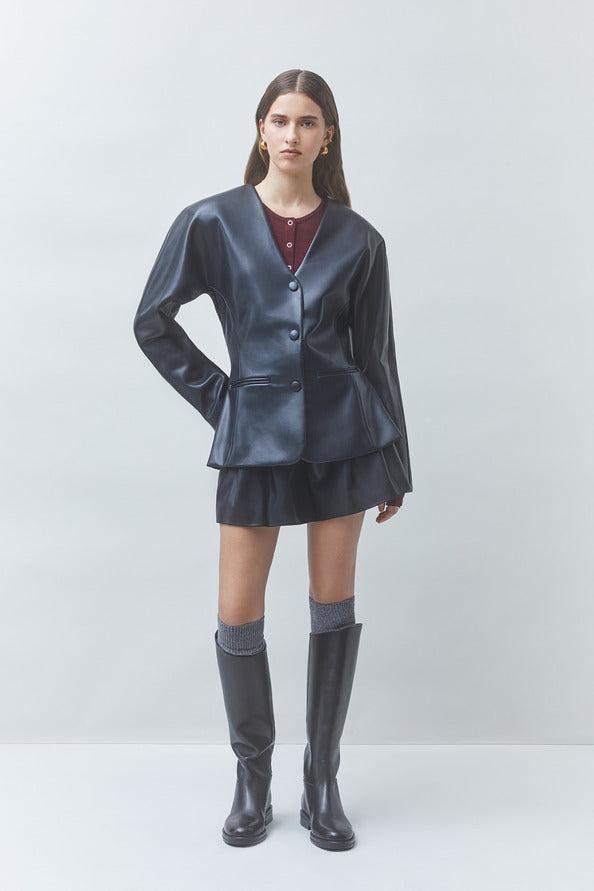 Woman wearing a metallic silver outfit with a jacket, skirt, and knee-high boots on a white background