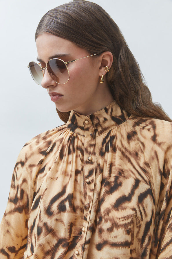 model wearing an animal print top with sunglasses on a white bakground