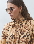 model wearing an animal print top with sunglasses on a white bakground