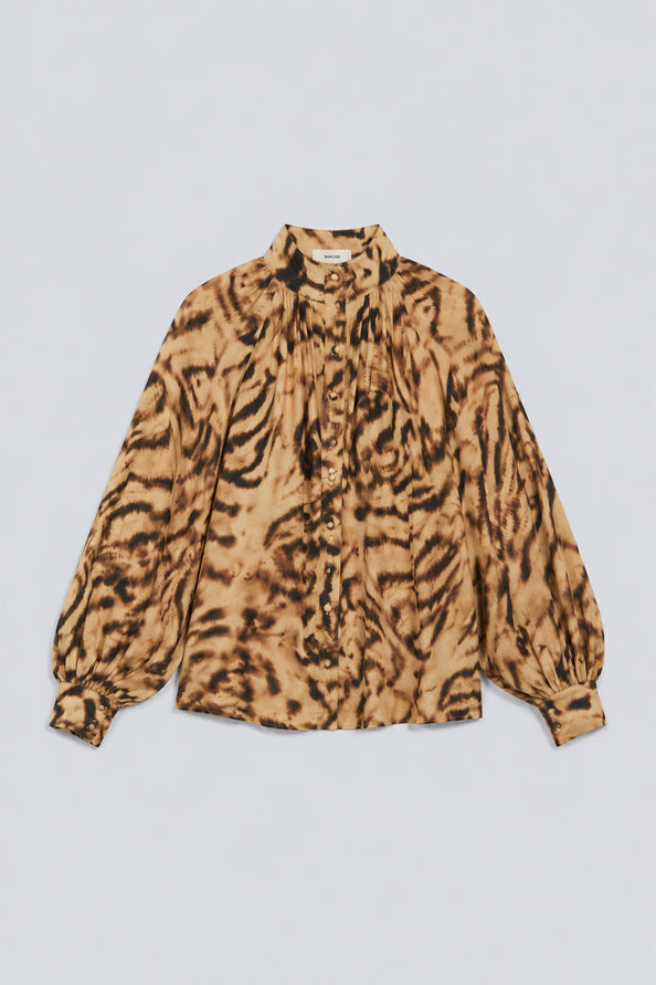 A long-sleeve blouse with a brown and beige tiger-stripe pattern, featuring a high gathered collar and a button-down front, laid flat against a light gray background.