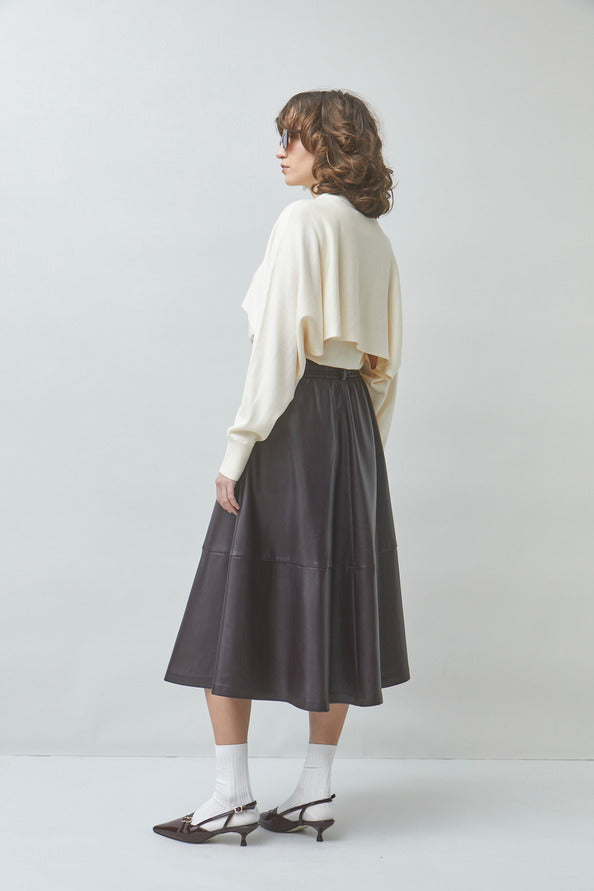 Woman wearing a white blouse and dark skirt on a plain background